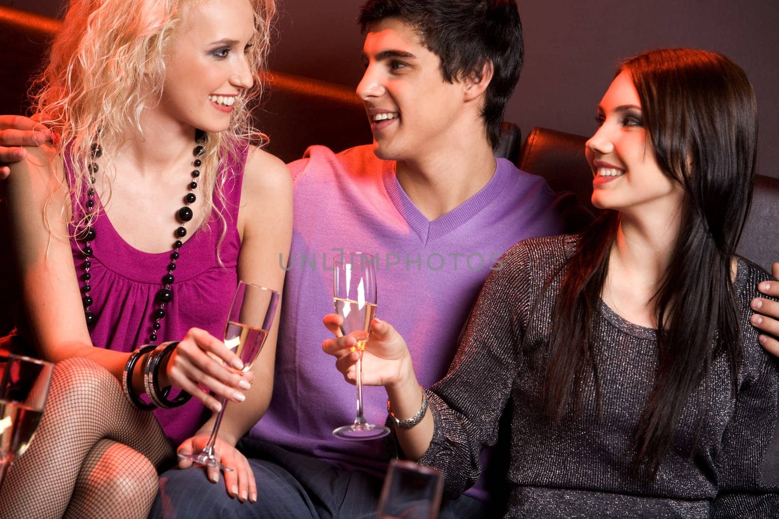 Portrait of smart young people holding champagne flutes and chatting with each other