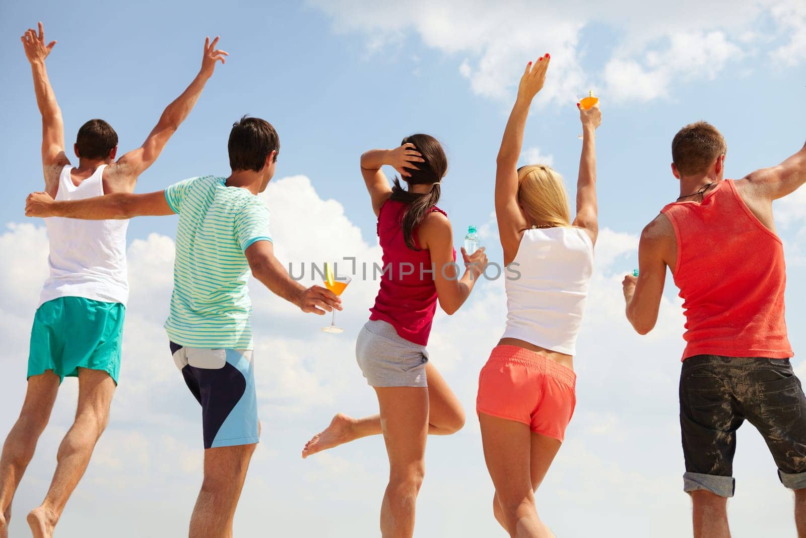 Backs of happy young friends dancing at beach party