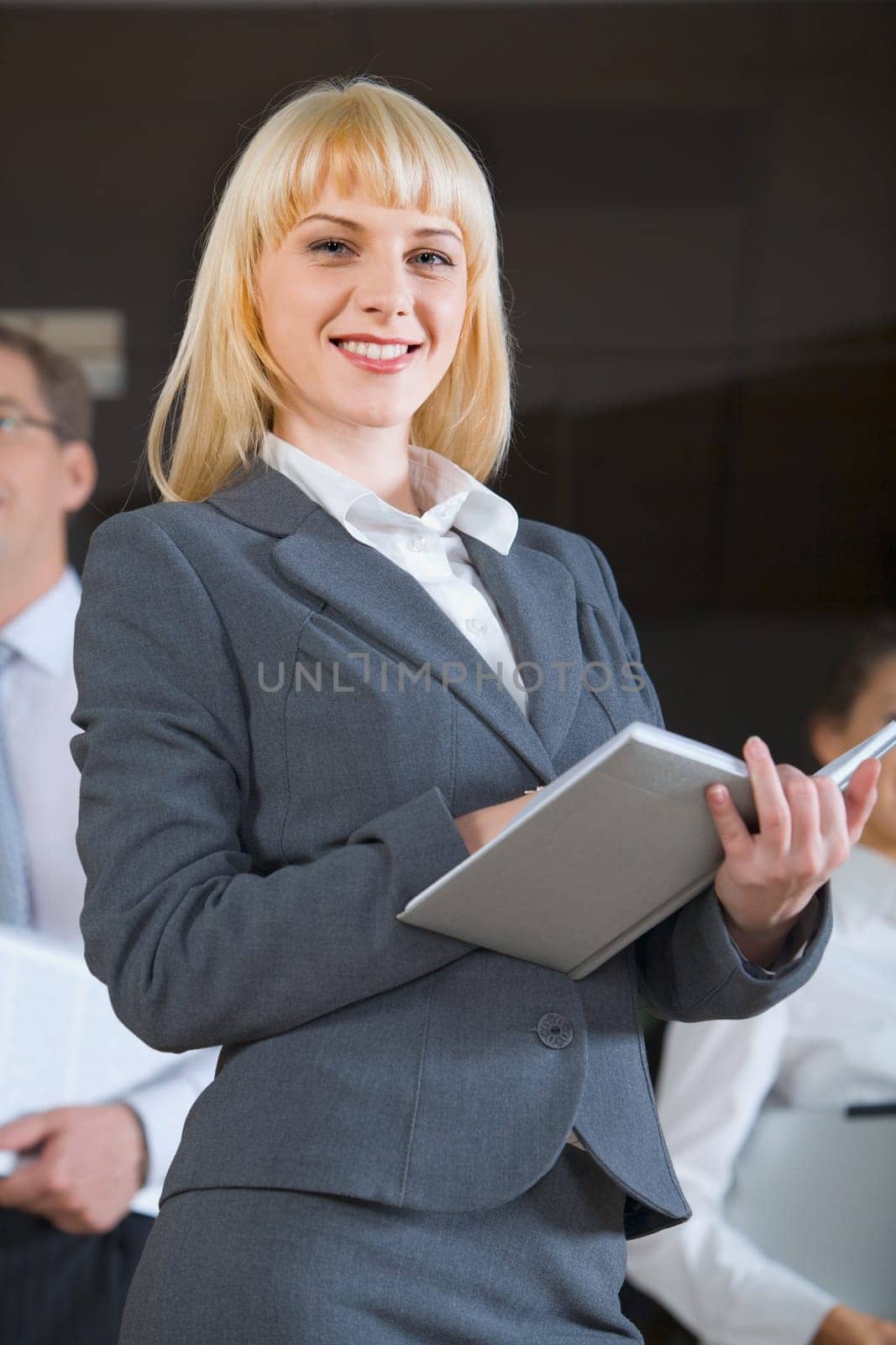 Portrait of confident business woman in suit holding the notepad on the background of people