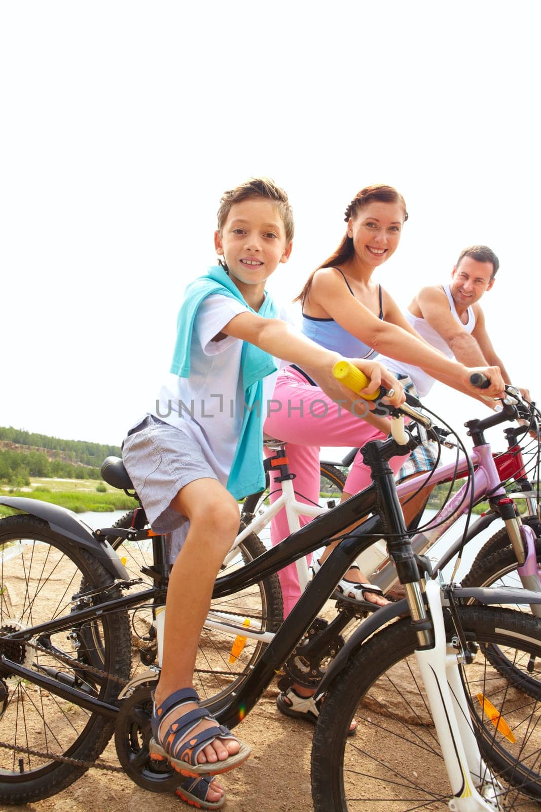 Portrait of family of three on bikes looking at camera and smiling