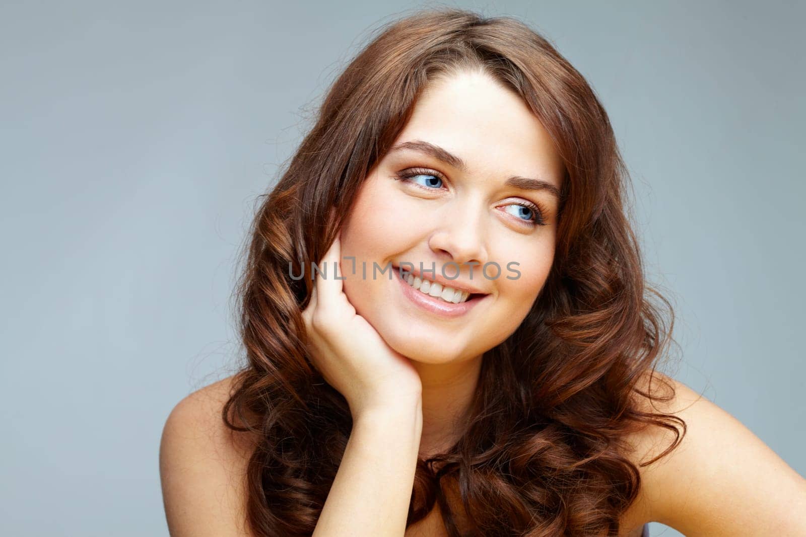 Portrait of feminine woman touching her face and looking aside