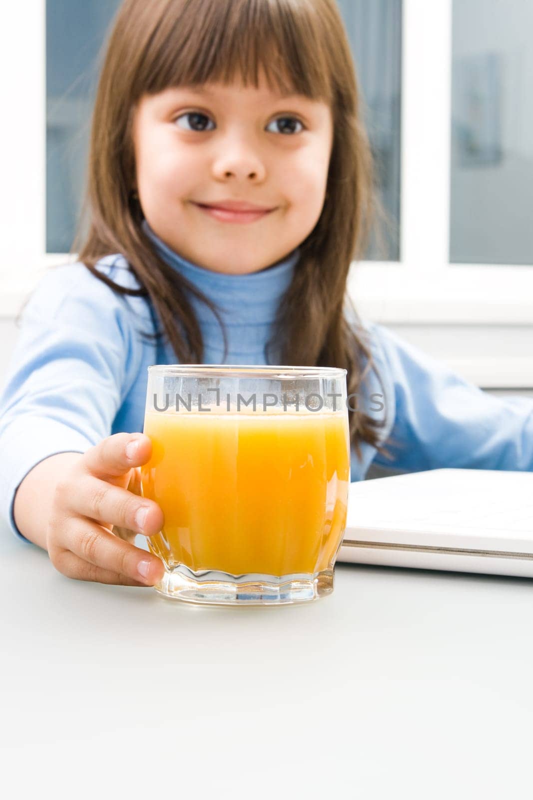 Close-up of positive childs hand touching a glass of orange juice