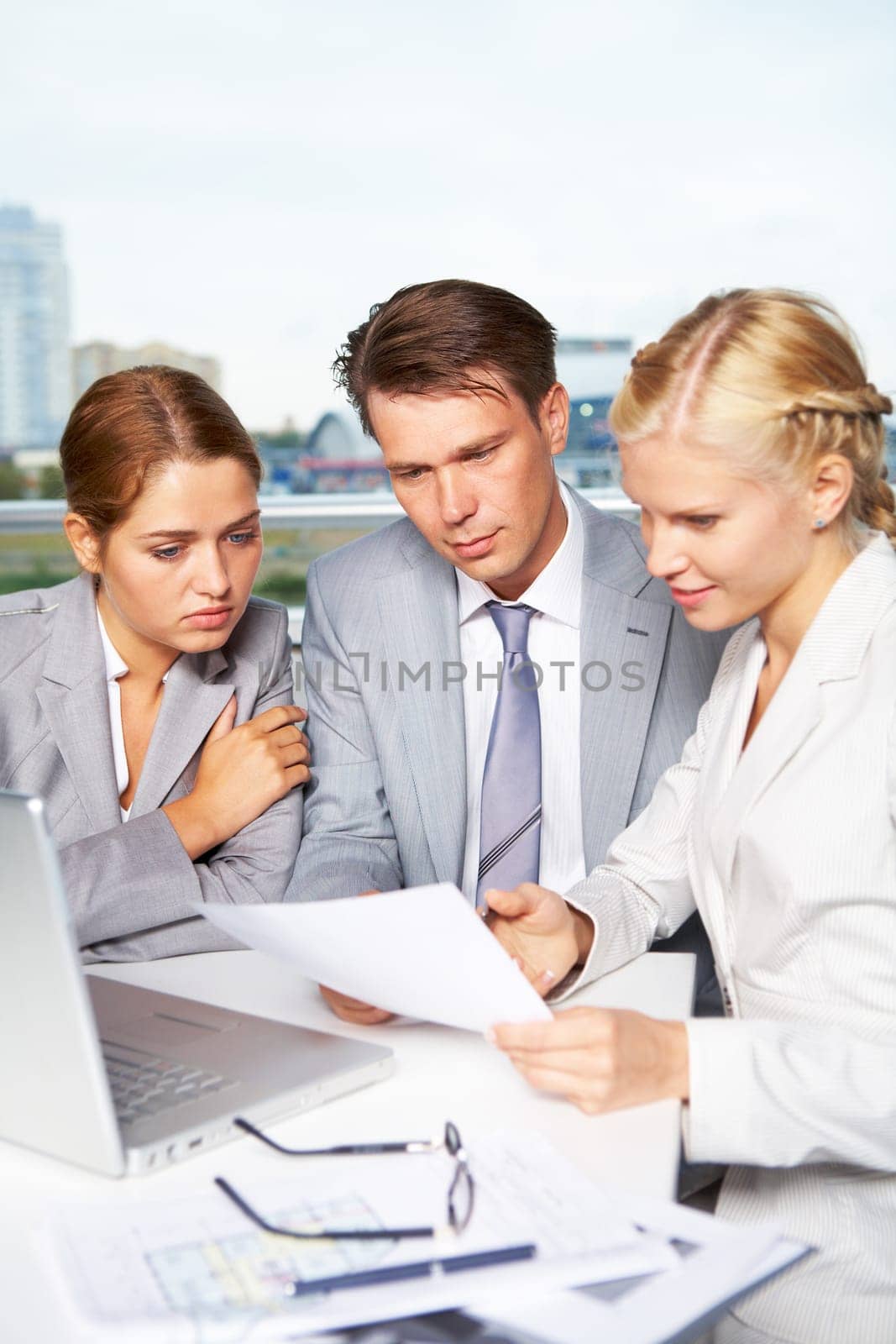 Image of successful businesspeople looking at document while discussing it in office