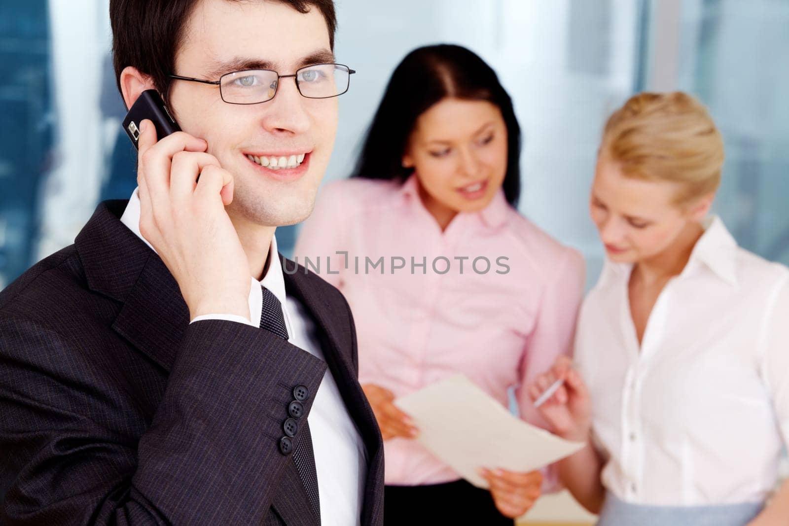 Image of handsome businessman speaking on the phone in working environment