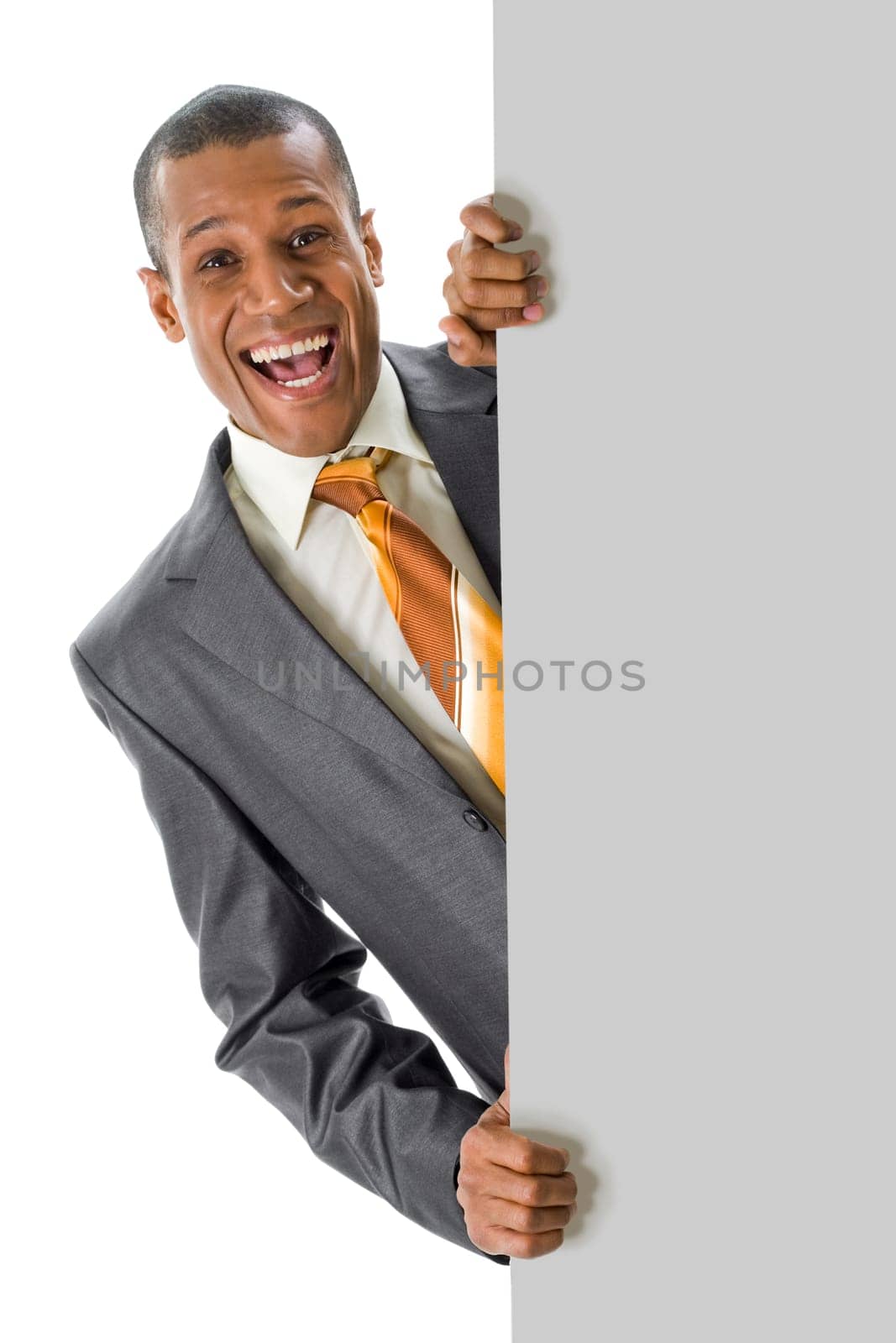 Image of joyful businessman peeping out of blank poster with your ad