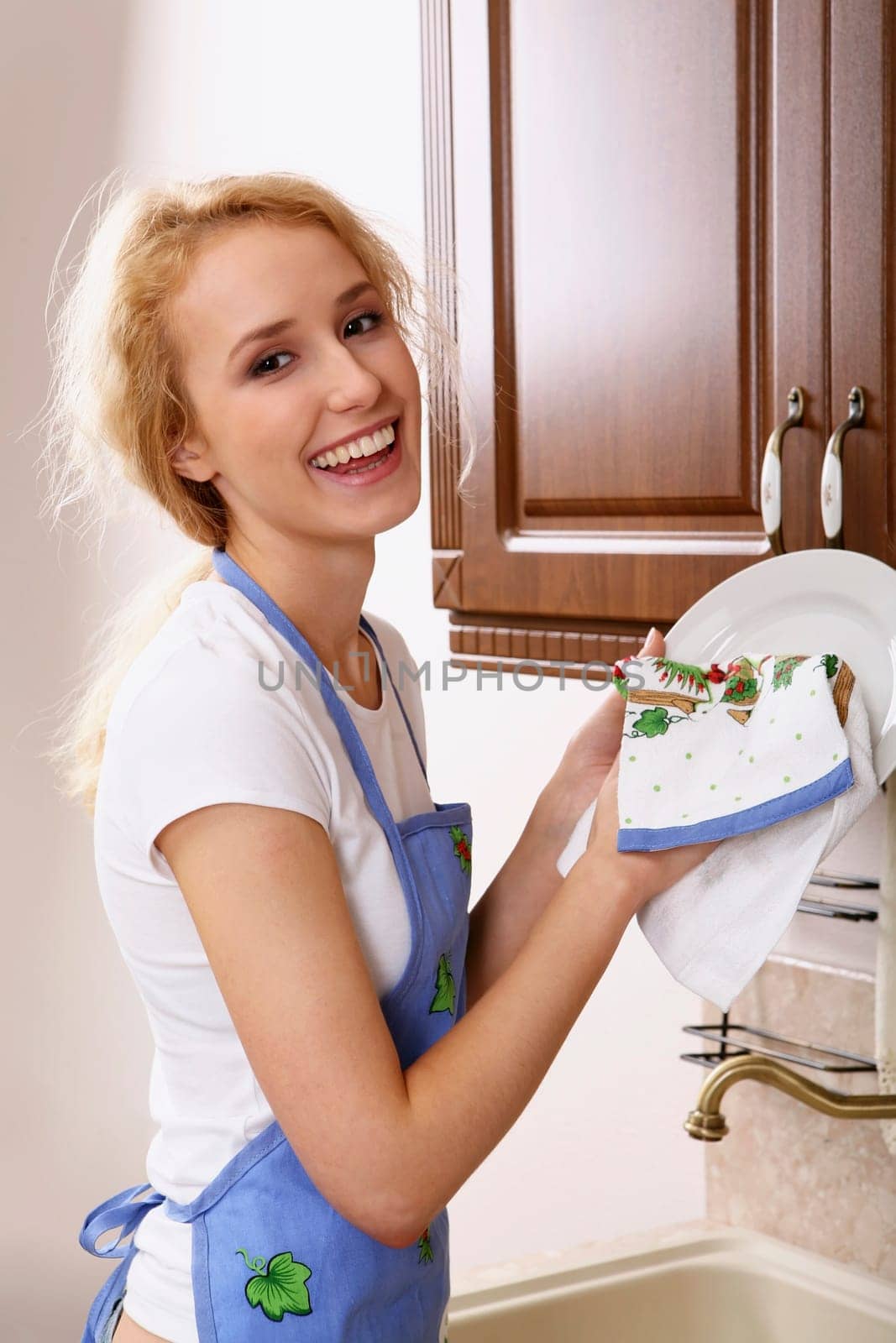 Smiling girl in the apron drying the dishes