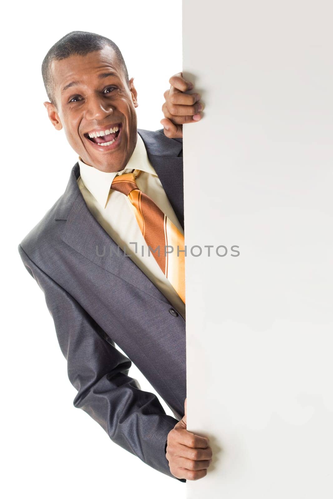 Image of joyful businessman peeping out of blank poster with your ad