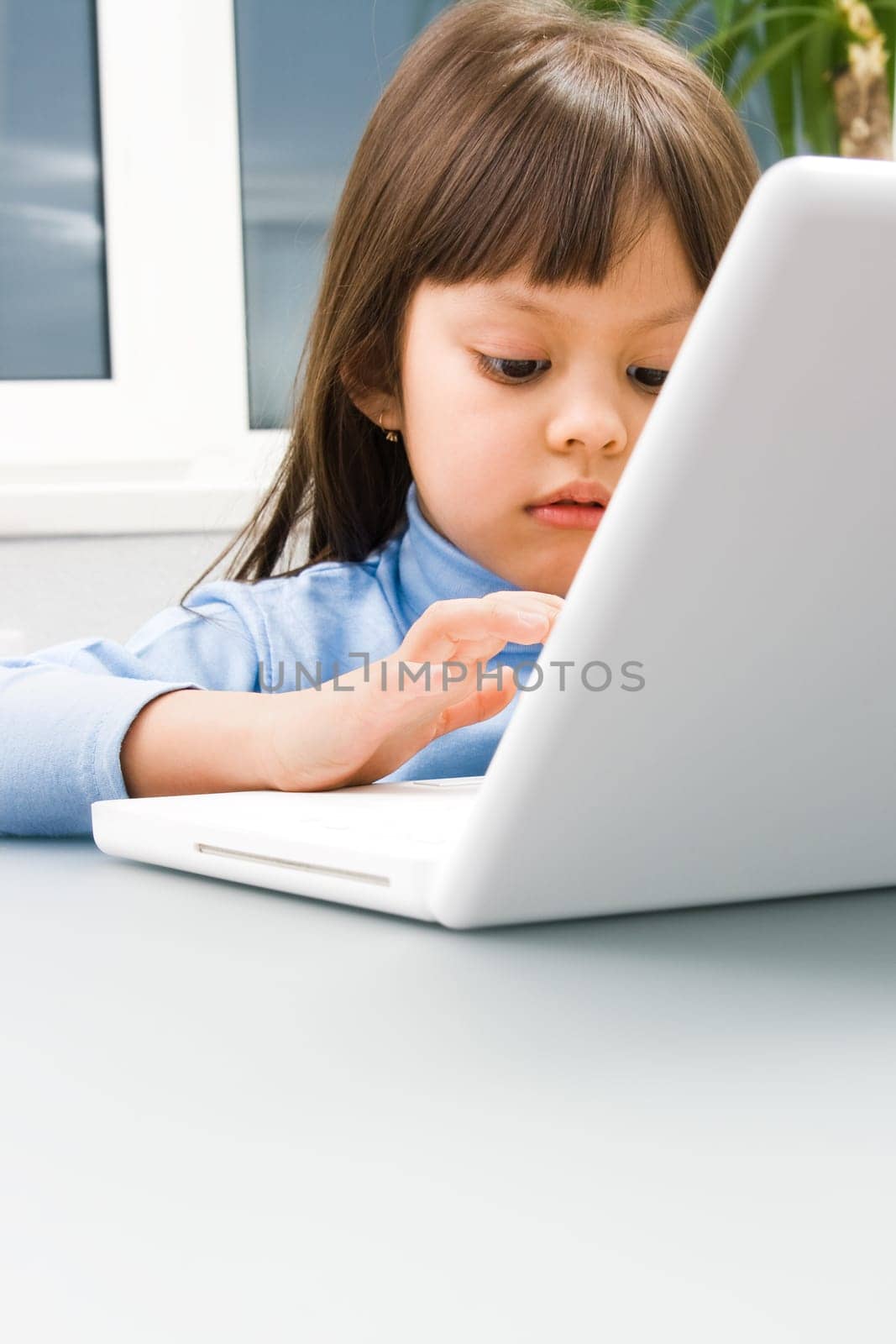 Close-up of childs palm over computer keyboard with female reader at background
