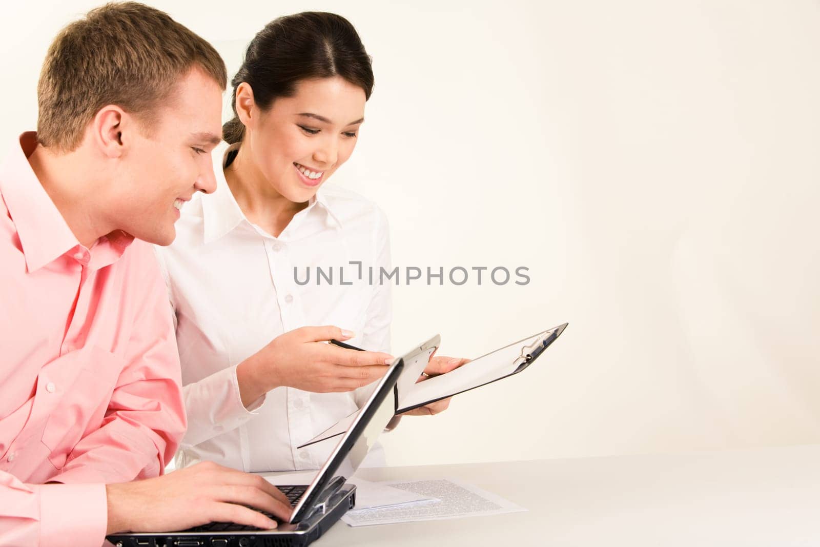 Photo of business partners sitting at workplace and looking at document with smiles