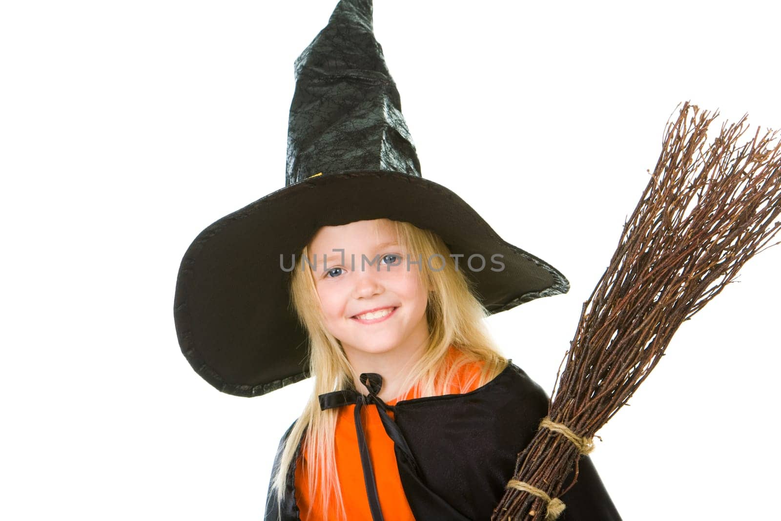 Photo of girl in halloween costume and broom smilling at camera