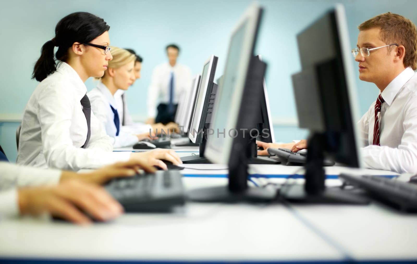 Businesspeople sitting at tables and looking at their monitors