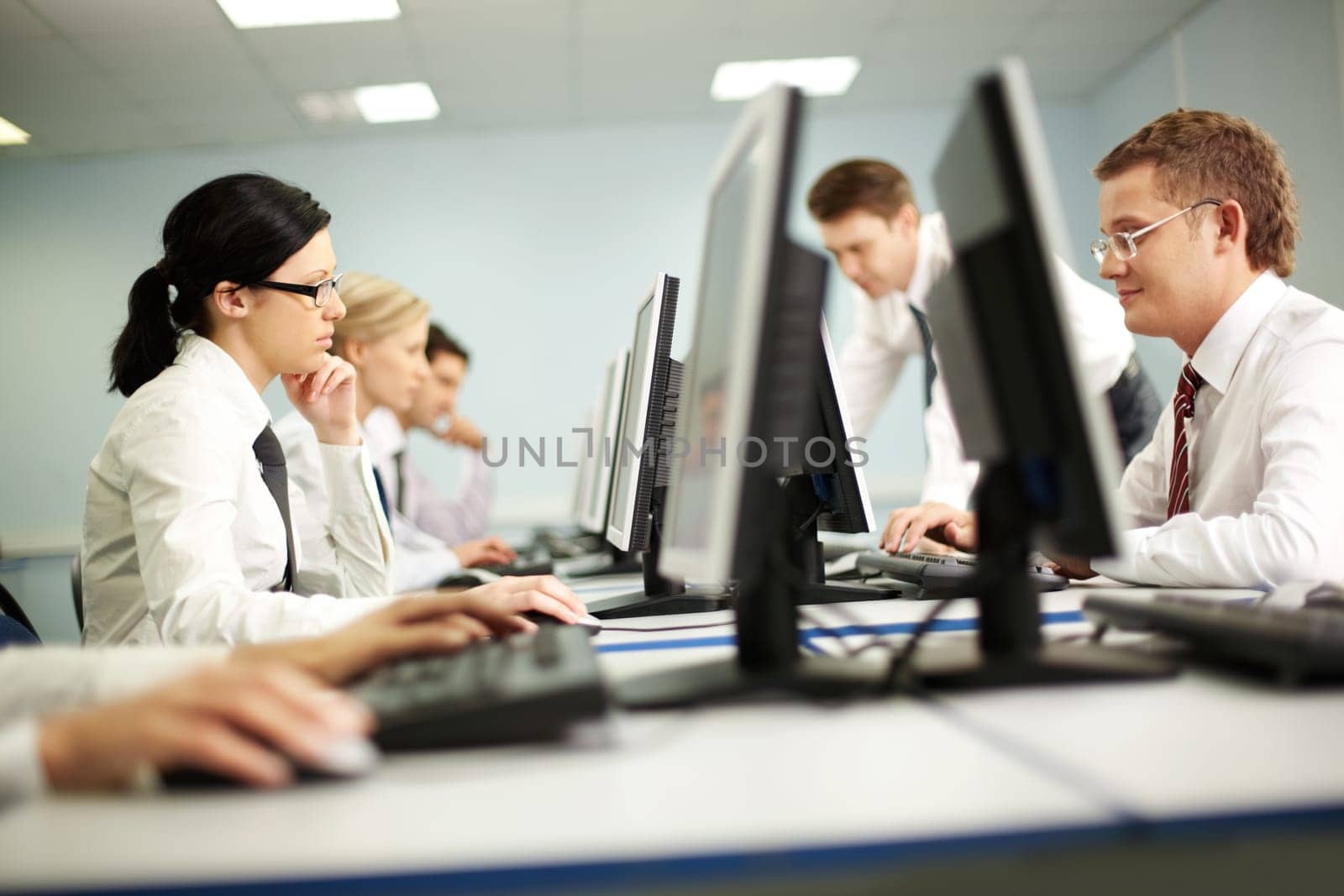 Businesspeople sit at tables and look at their monitors