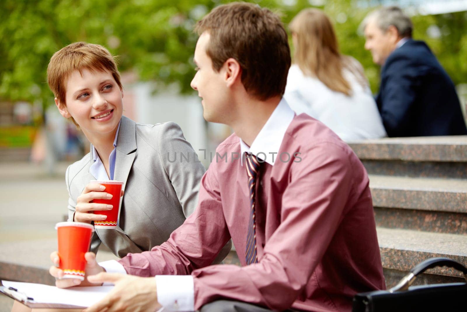 Portrait of happy business partners chatting during break outside at summer