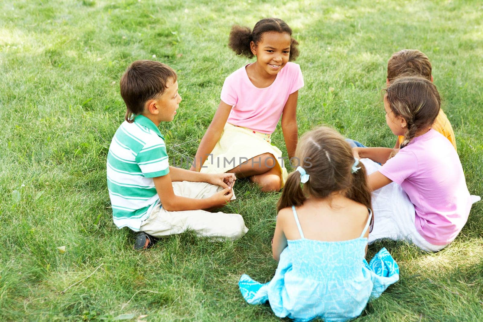 Portrait of cute kids seated on green grass and chatting