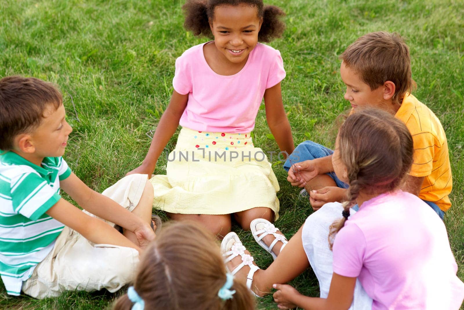 Portrait of cute kids seated on green grass and chatting