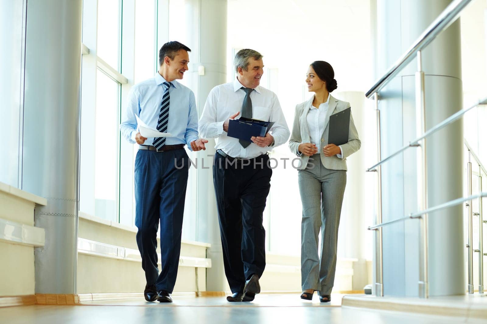 Confident business partners walking down in office building and discussing work