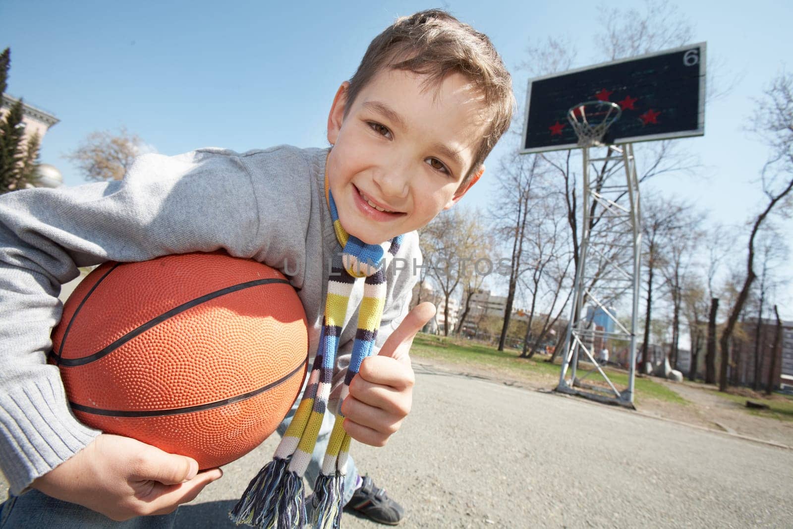 Image of happy boy with ball looking at camera outdoors