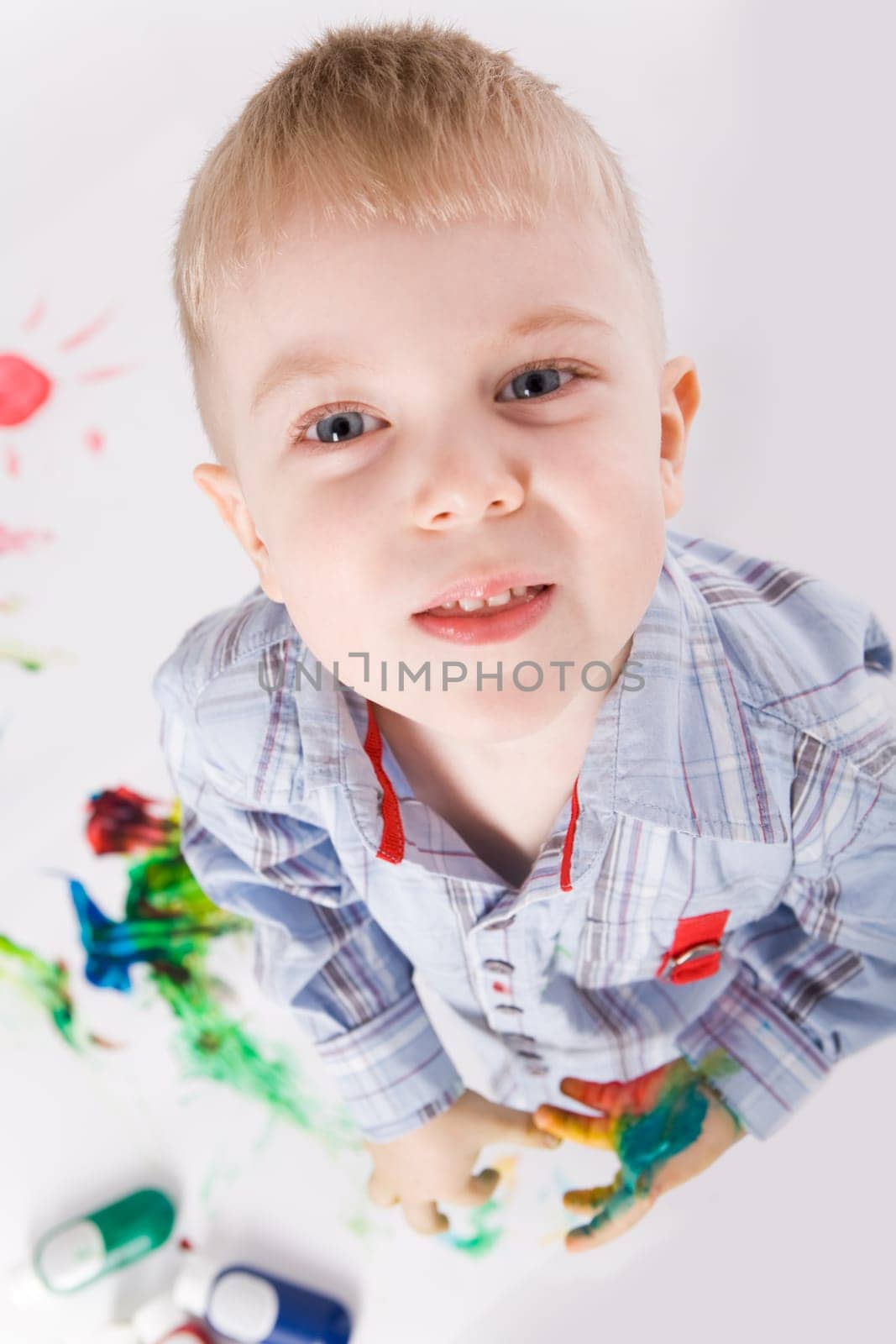 Above shot of preschooler with painted hands looking at camera