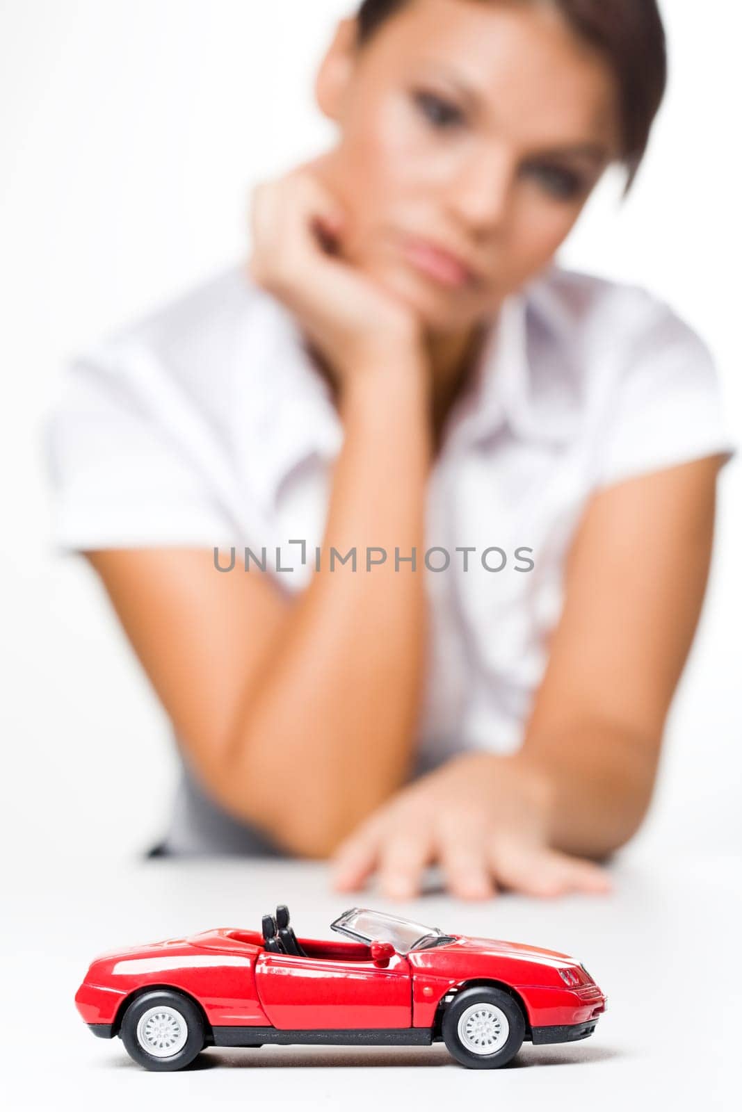 Photo of small red toy automobile with thinking woman at background