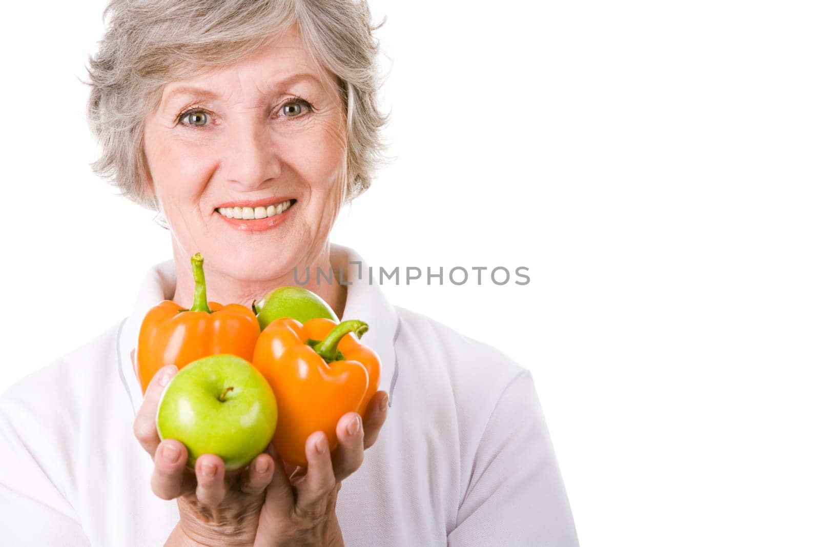 Portrait of aged female holding apples and peppers in hands
