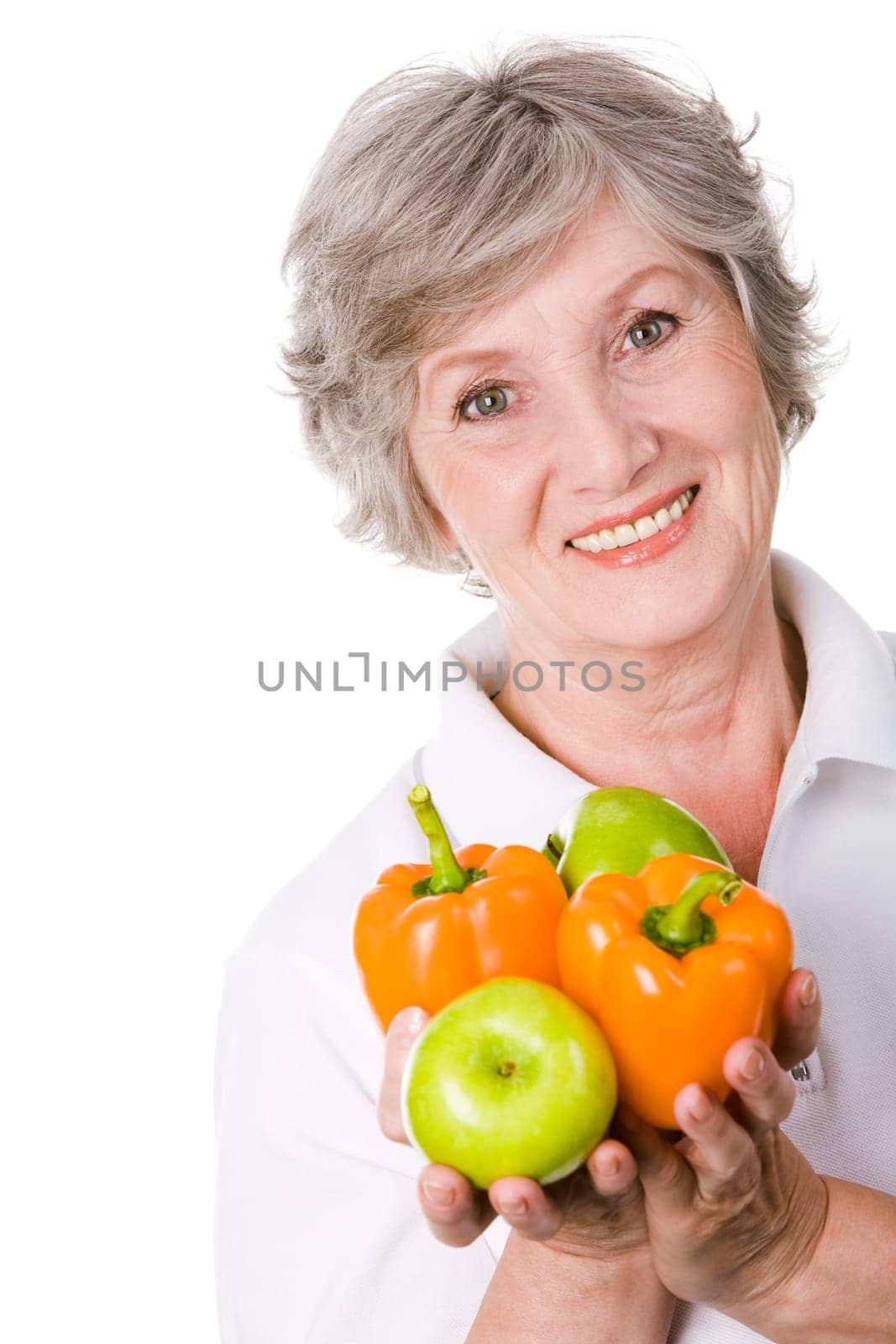 Portrait of aged female holding apples and peppers in hands