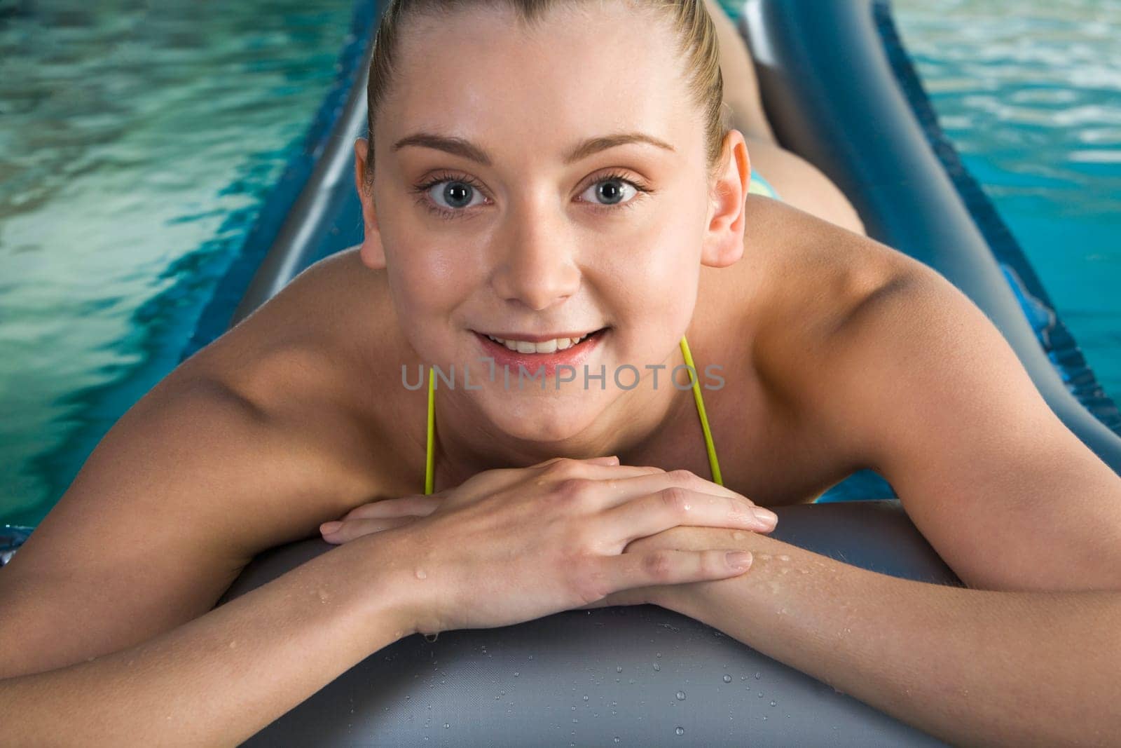 Smiling woman lies on the water mattress in the pool