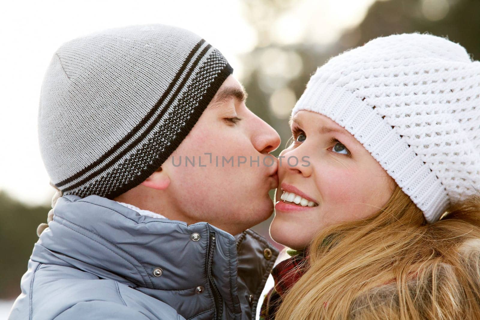 Portrait of happy young man kissing beautiful woman in winter