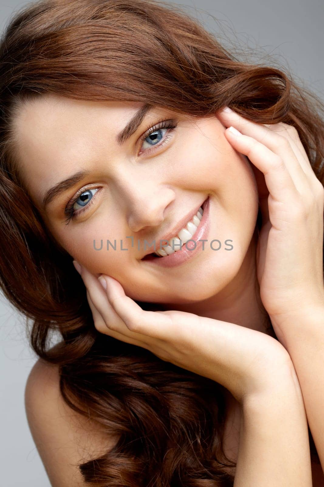 Portrait of charming girl touching her face and looking at camera