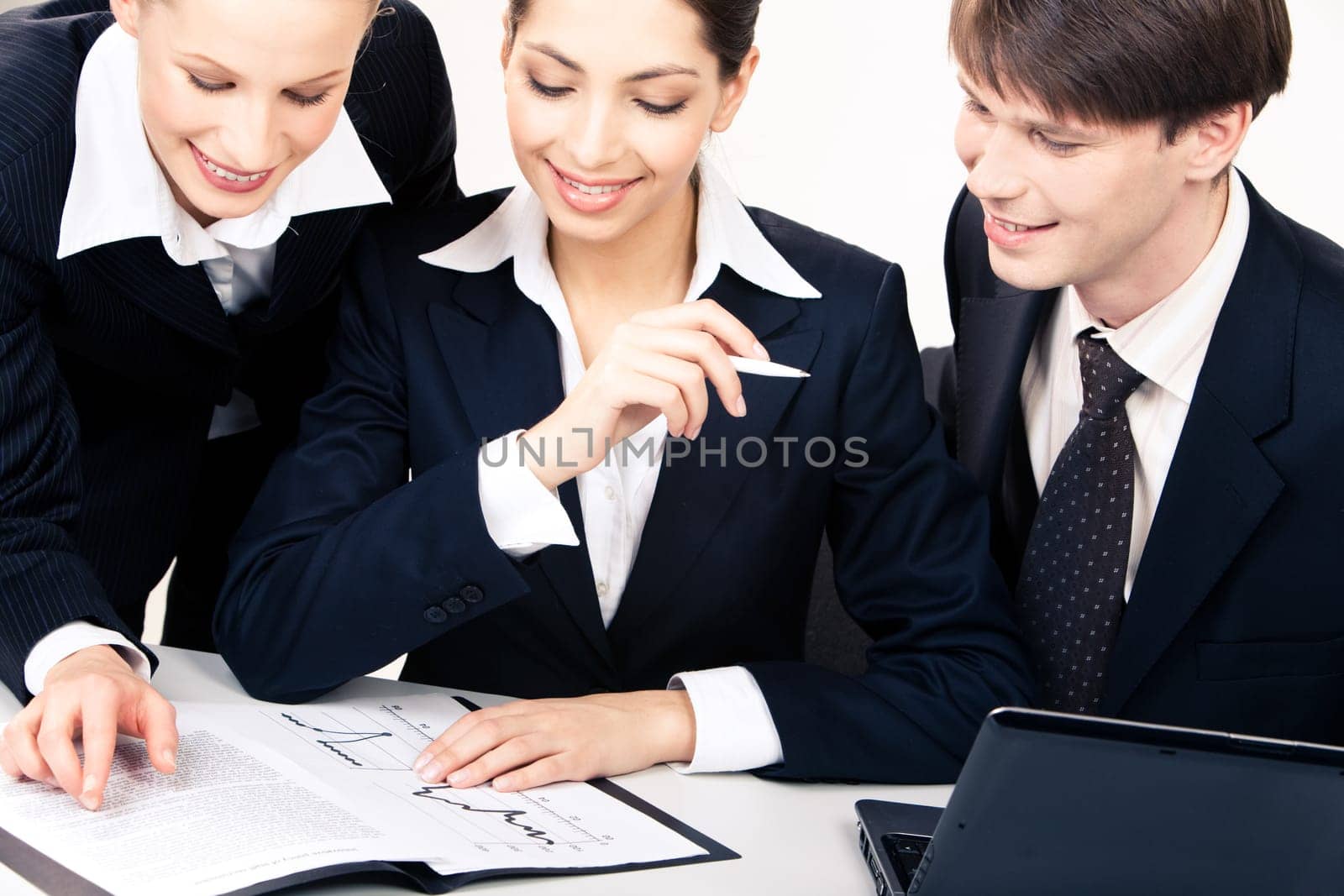 Photo of business women looking at documents at table with smiling man sitting near by
