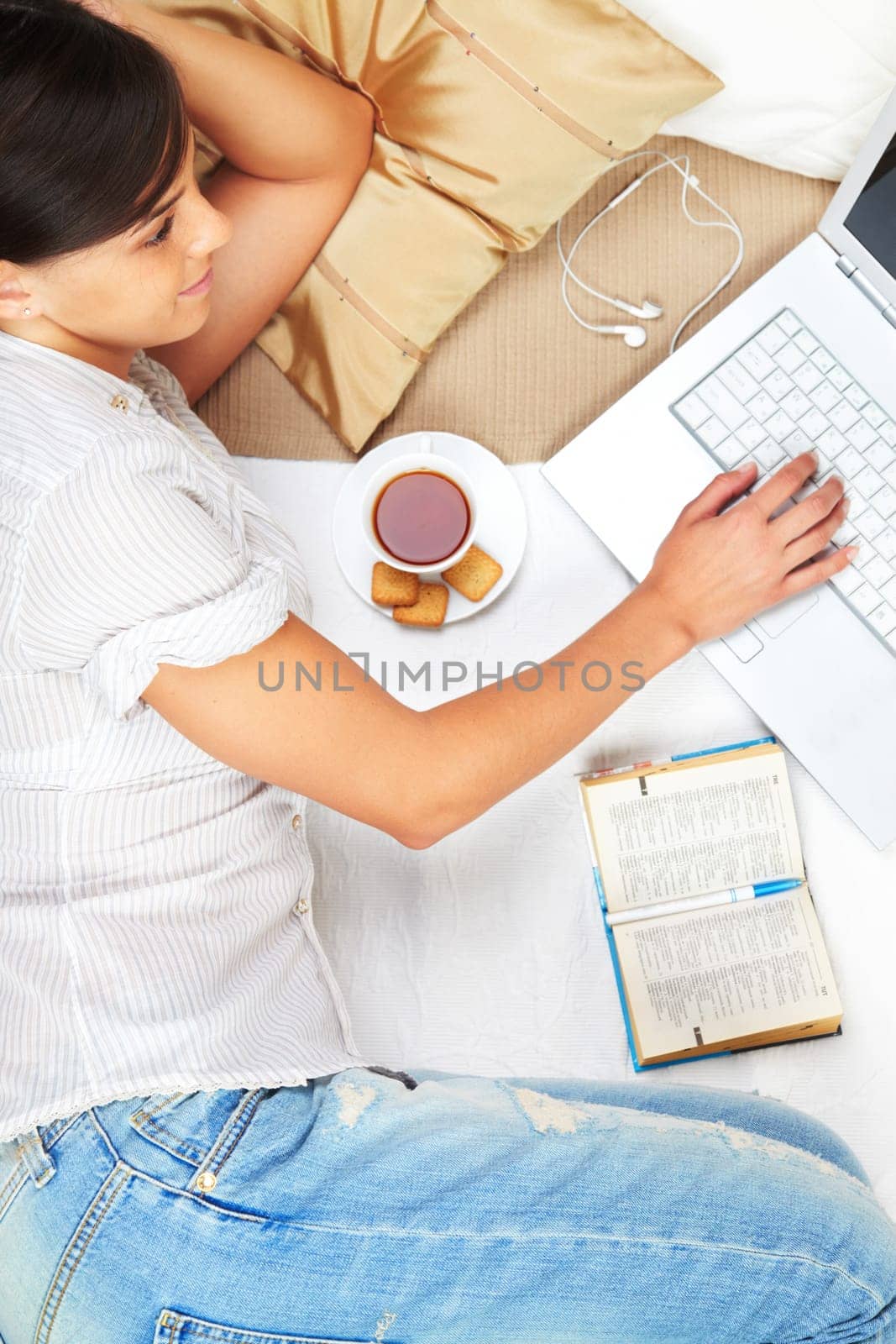 A young girl working on computer in bed