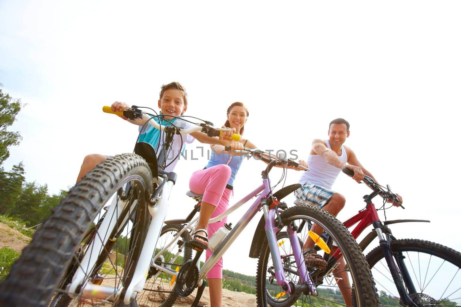 Family of three sitting on bikes, looking at camera and smiling