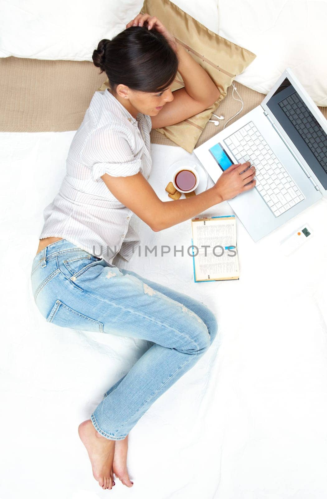 A young girl working on computer in bed