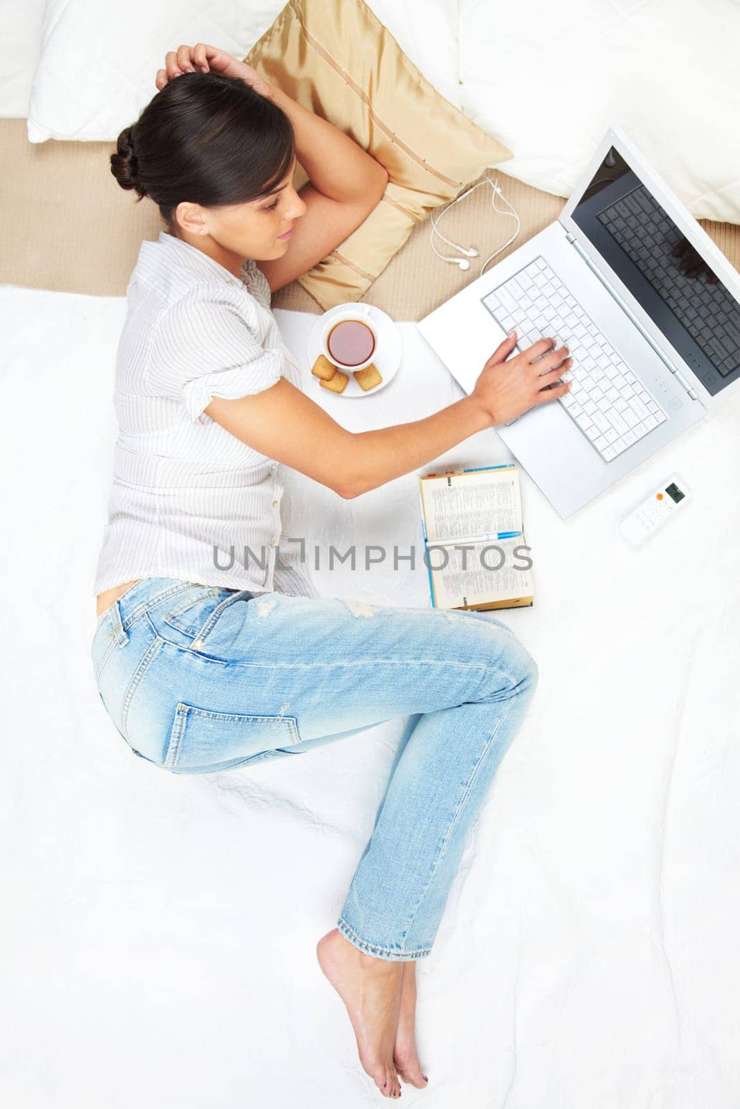 A young girl working on computer in bed
