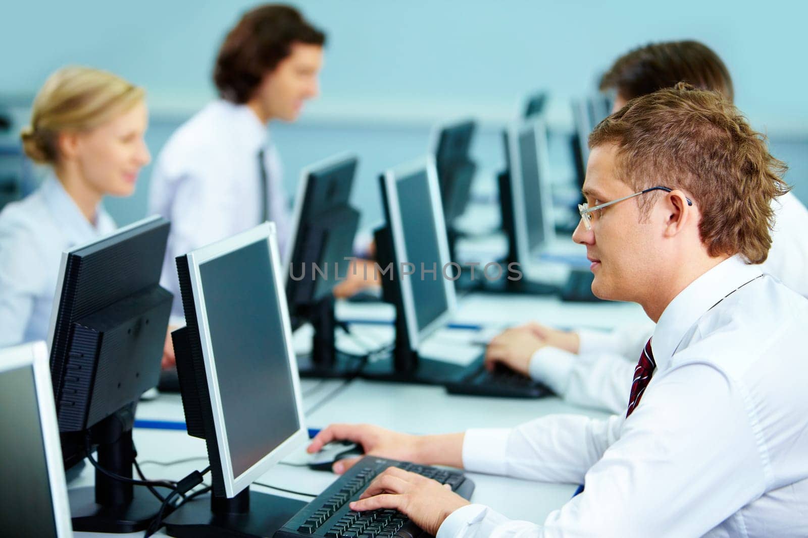 Smart businesspeople typing at workplaces in computer room