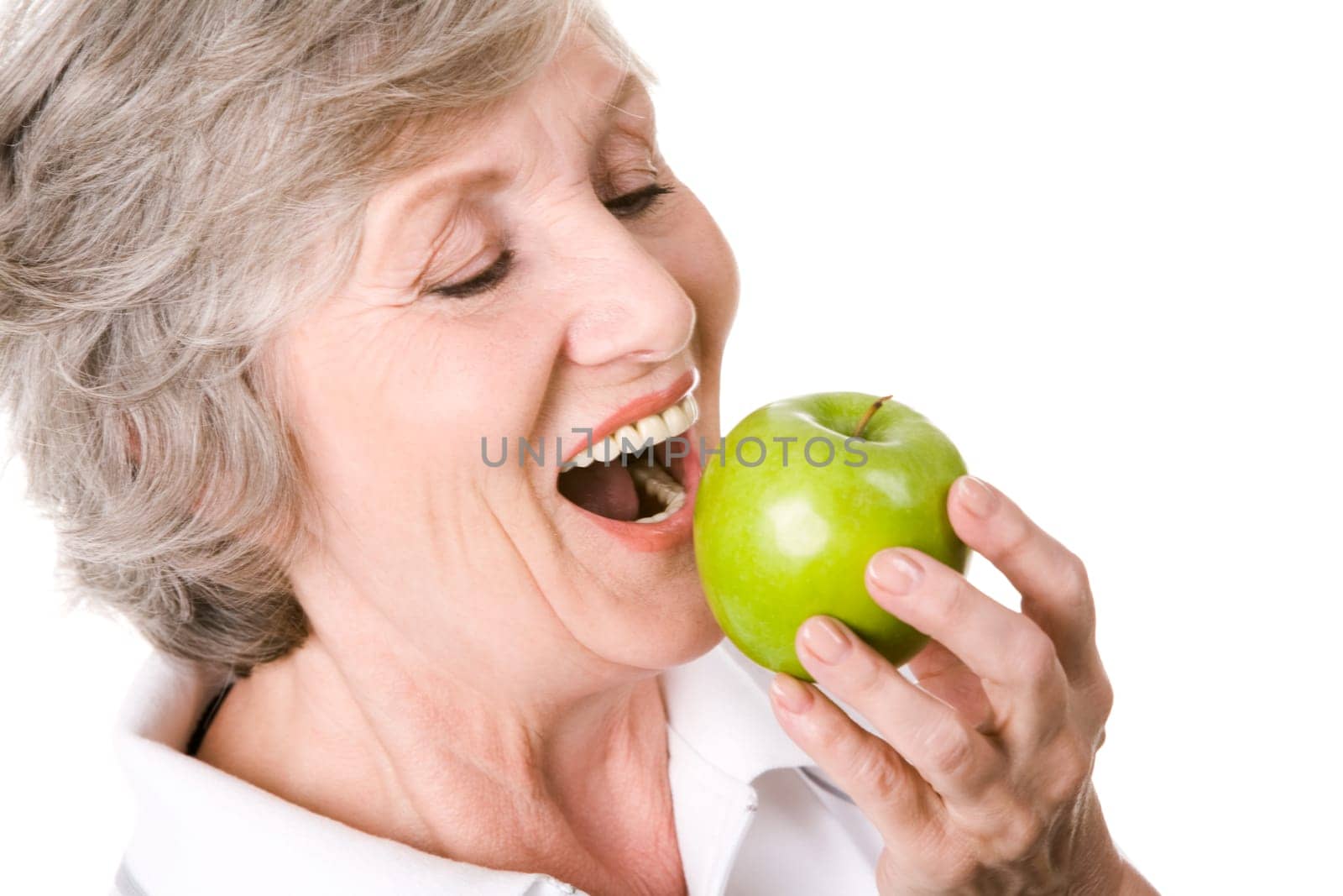 Portrait of senior woman holding an apple and eating it