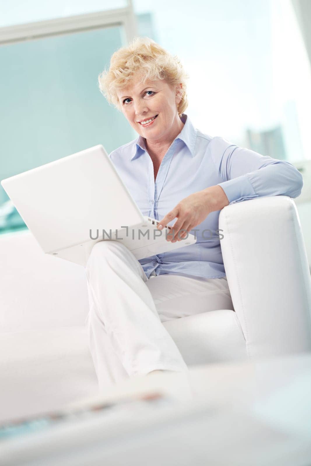 Portrait of friendly aged woman typing and looking at camera