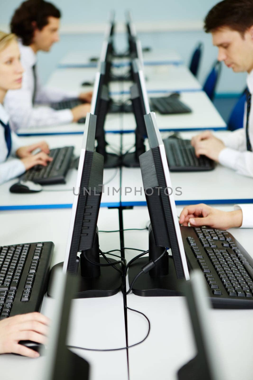 Business people sit at the tables with monitors on its in line