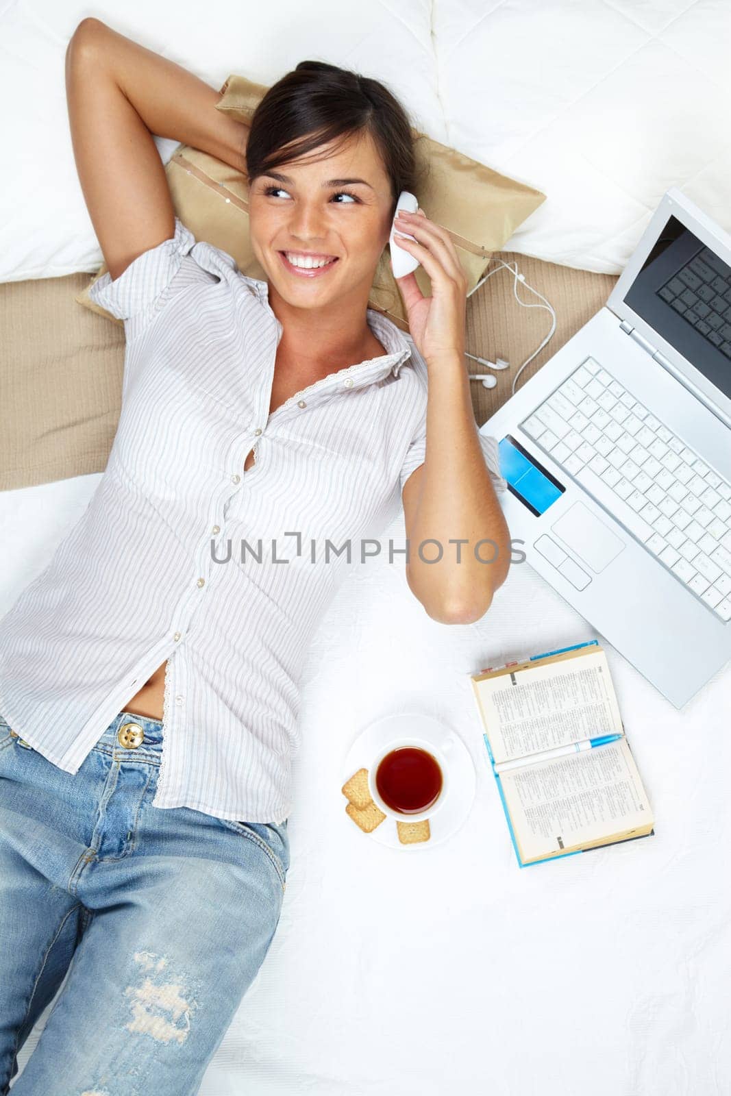 A young girl lying in bed and talking on her mobile phone