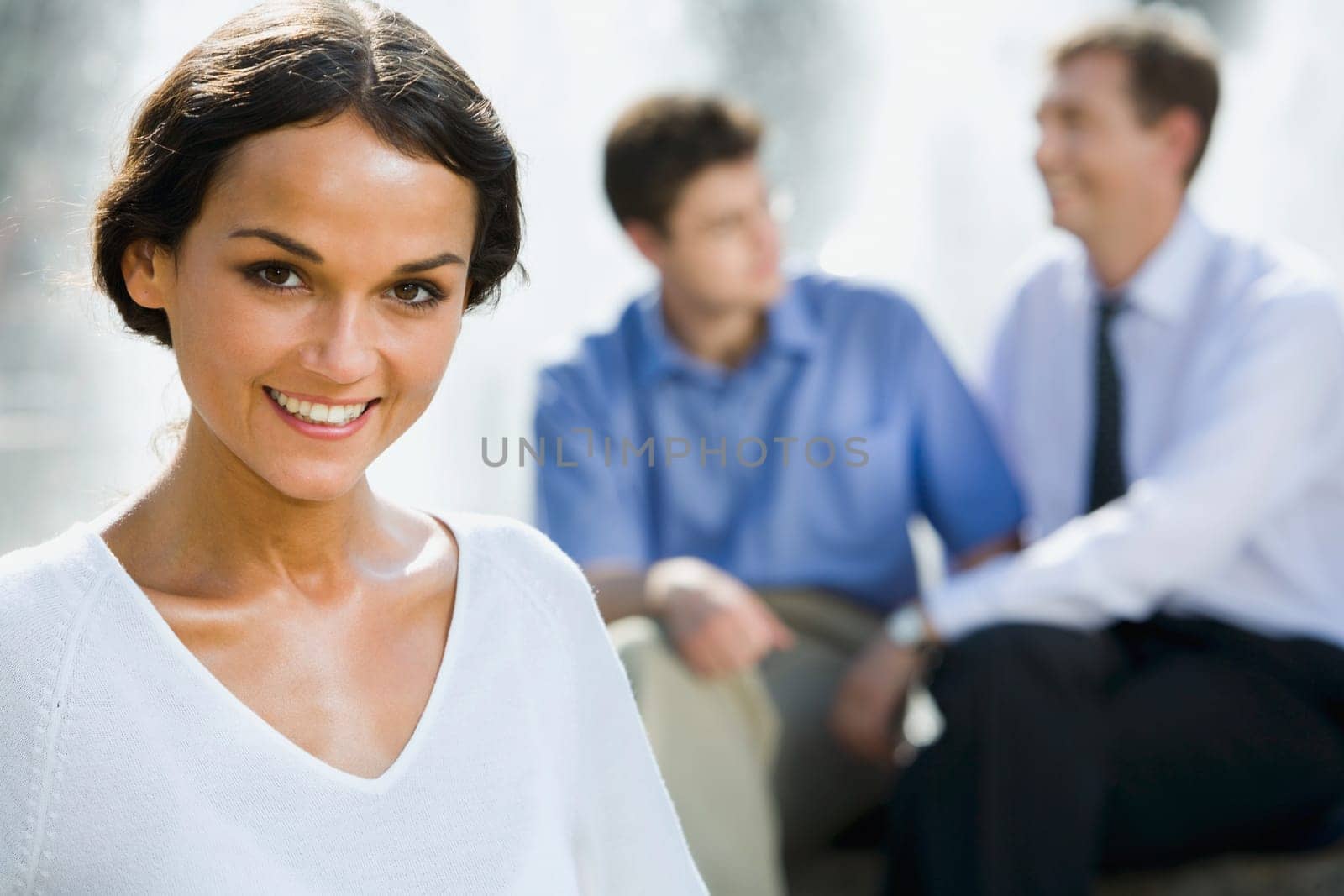 Successful young woman on the background of two businesspeople outside