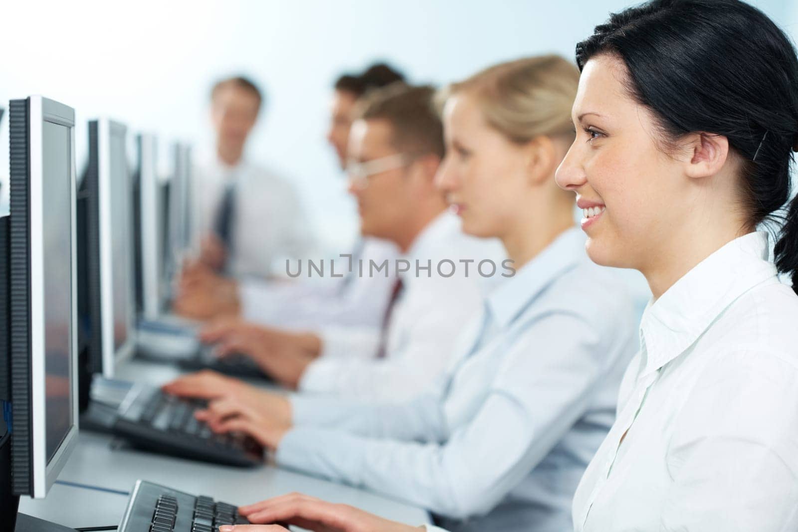 Close-up of a happy businesswoman working on computer among the others