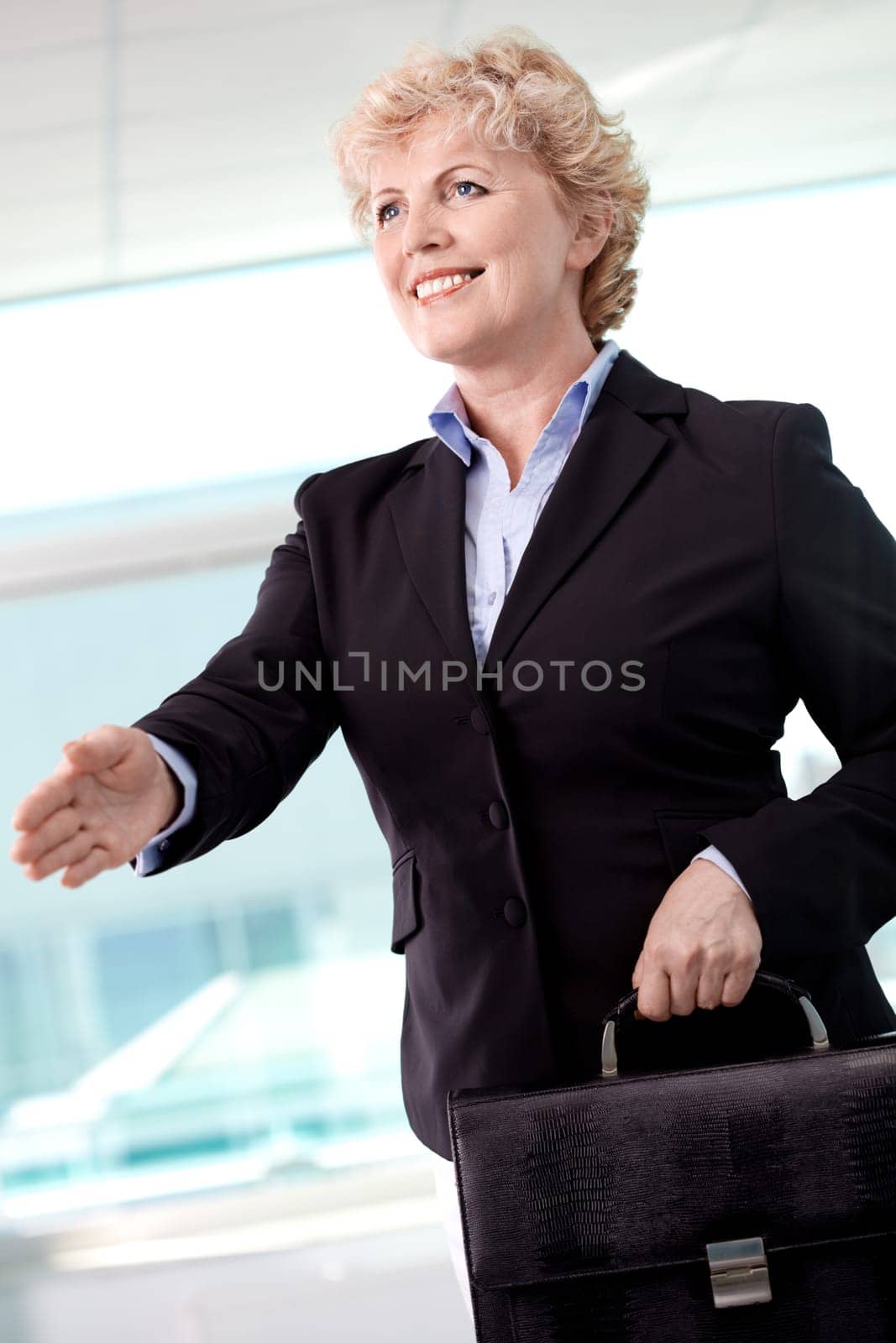 Portrait of smiling middle aged businesswoman with briefcase giving her hand for a handshake
