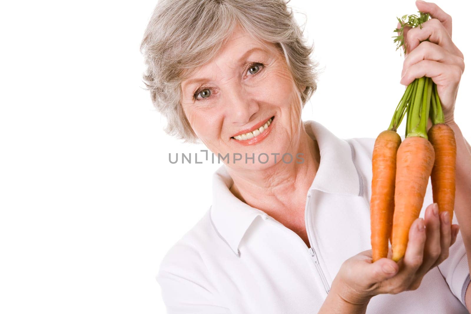 Portrait of elderly woman with ripe carrots smiling at camera over white background