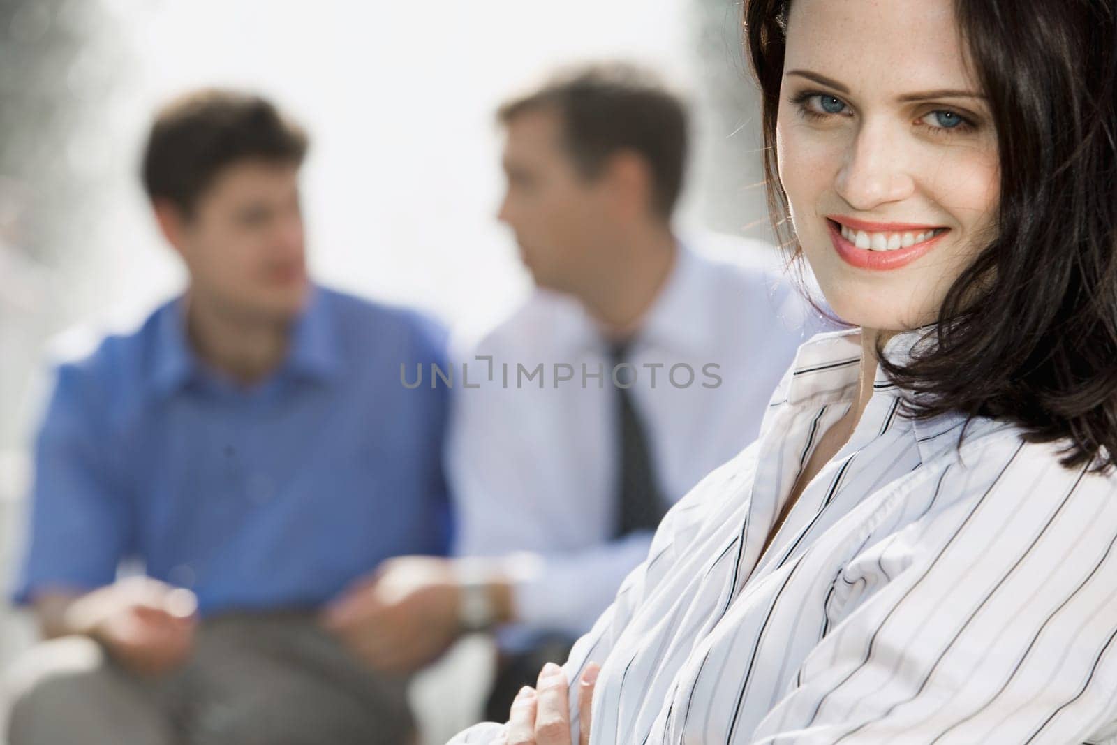 Portrait of successful young woman on the background of two businesspeople