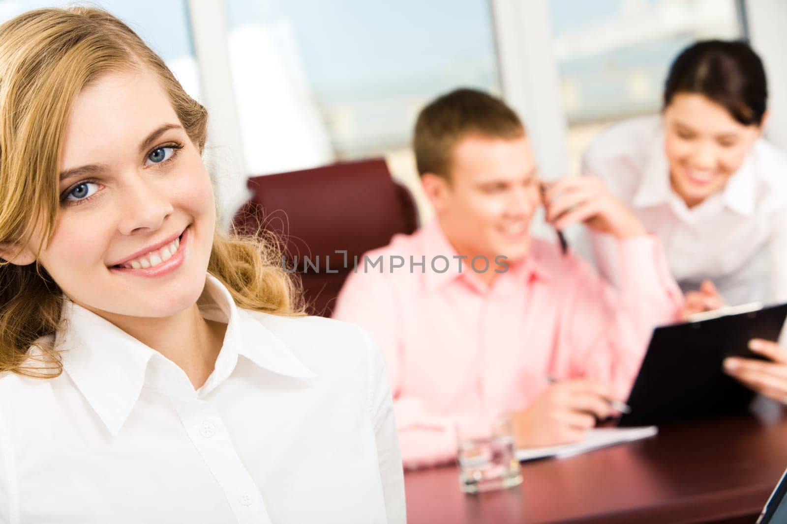 Portrait of blonde woman looking at camera in working environment in office