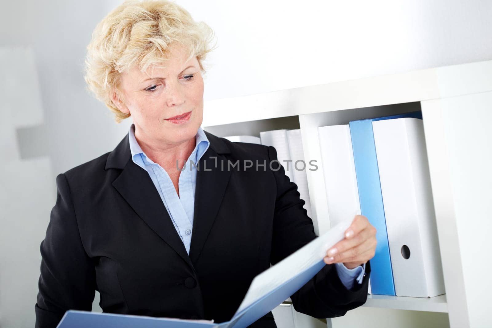 Portrait of middle aged businesswoman reading paper in office