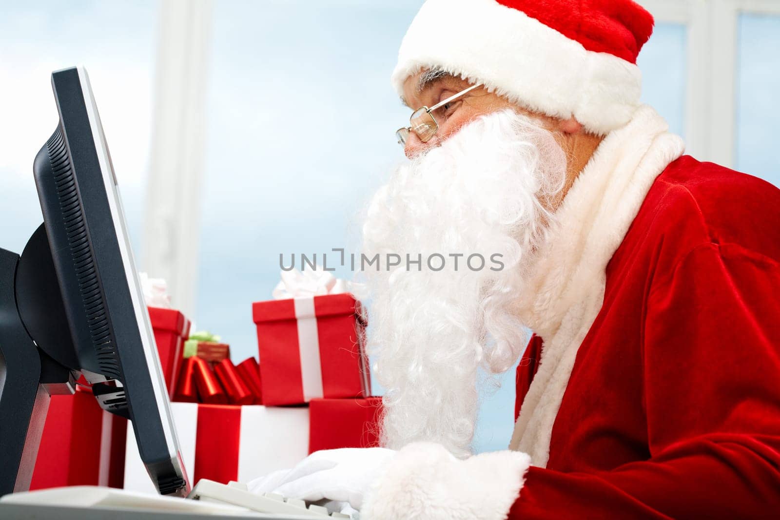 Portrait of Santa Claus in front of computer monitor