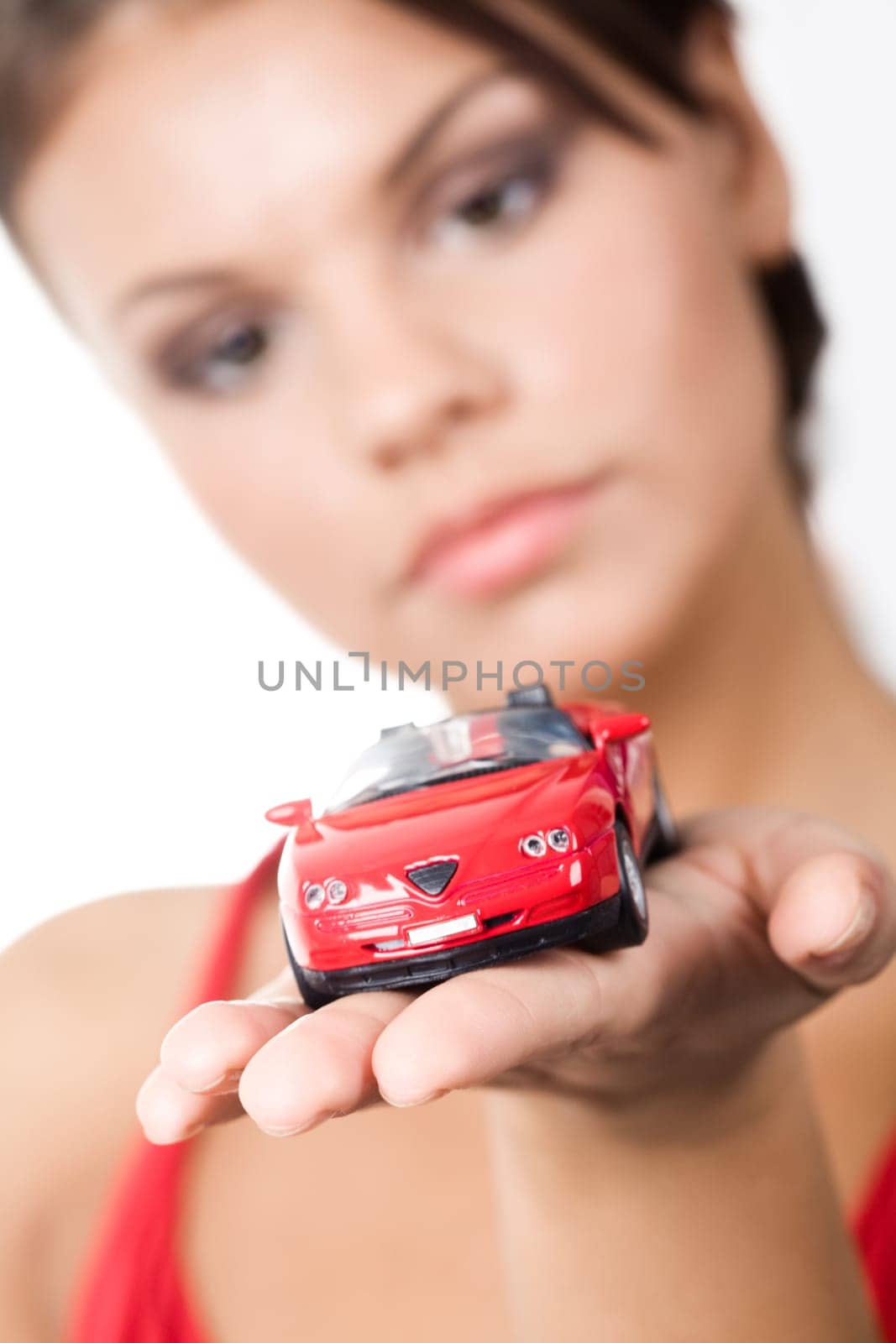Close-up of red toy pick-up on palm with womans face at background
