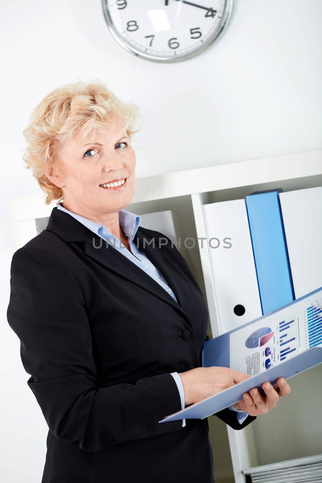 Portrait of smiling middle aged businesswoman with document looking at camera