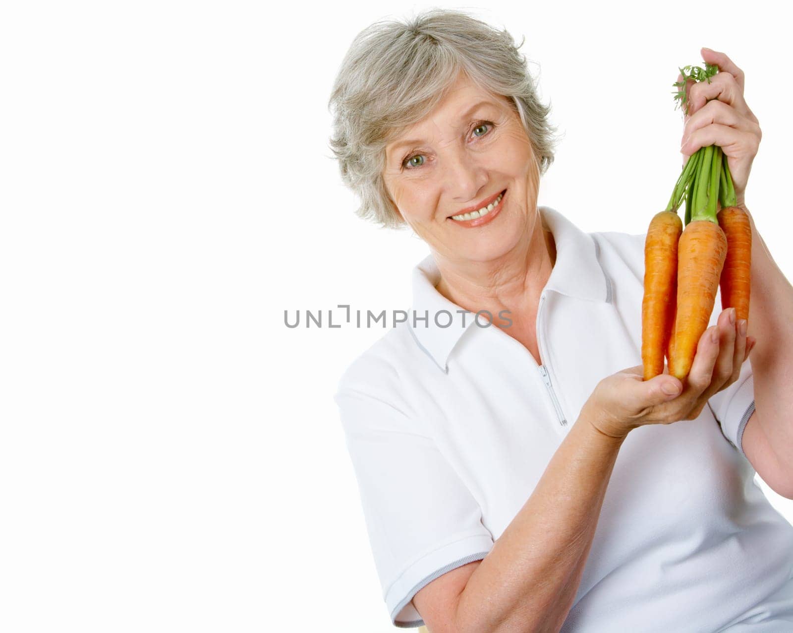Portrait of elderly woman with ripe carrots smiling at camera over white background