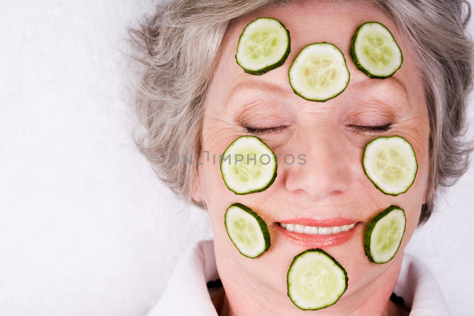 Face of mature woman with cucumber slices on it